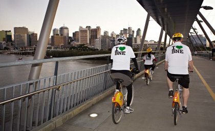 Two men on bicycles riding over a bridge on the Brisbane River